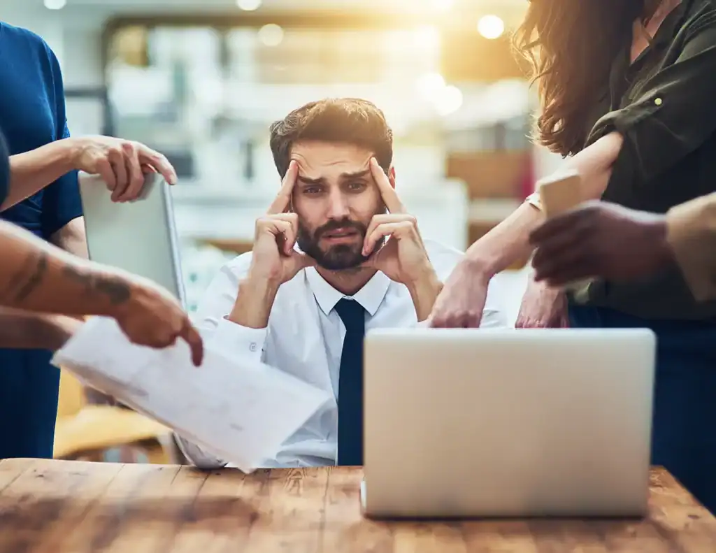 Young businessman stressed with work deadlines and multitasking in modern office.